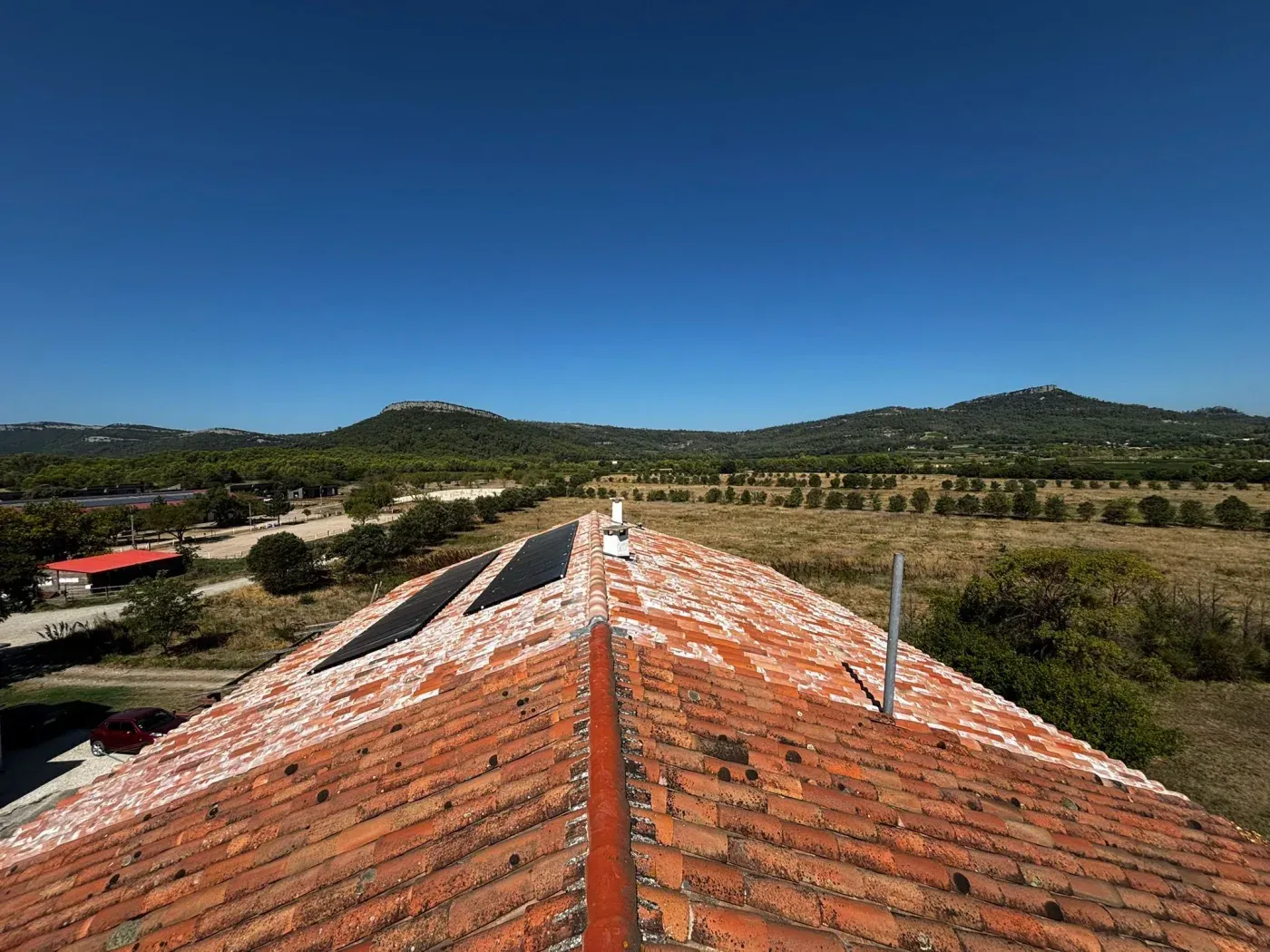 Toiture en tuiles canal reprise, avec la garrigue du Gard en arrière-plan