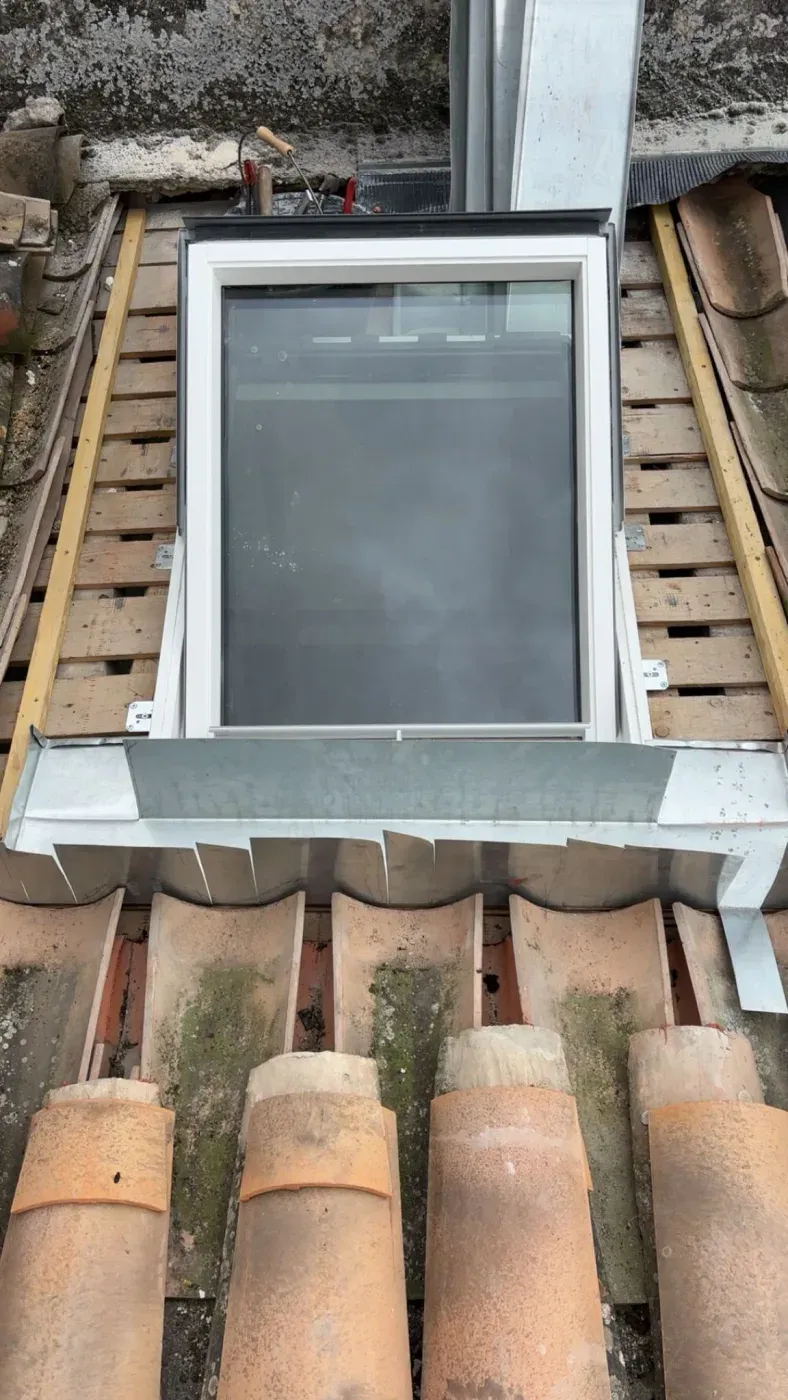 Installation d'une fenêtre de toit en cours sur une couverture en tuiles
